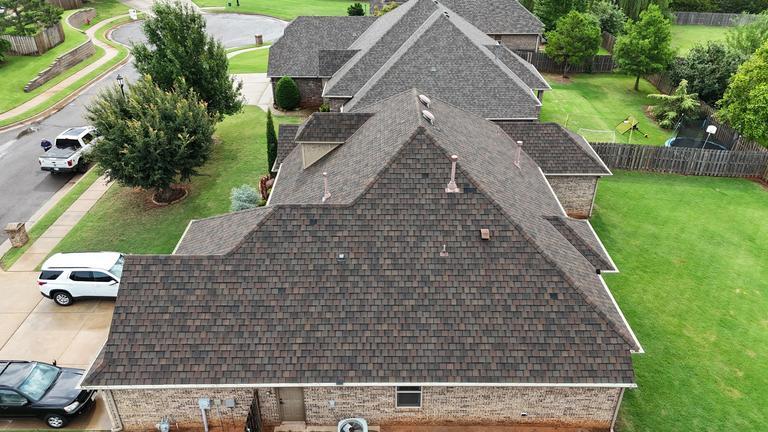 Classic brick home with warm-toned shingle roof in Edmond, Oklahoma